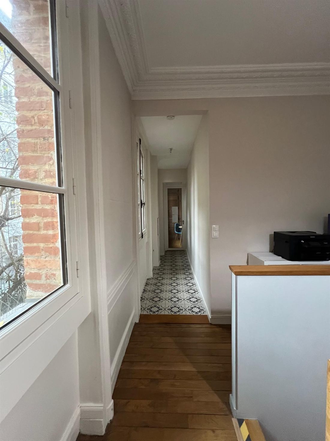 Palier lumineux avec carreaux de ciment et fenêtre donnant sur la cour
