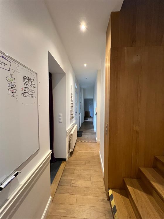 Couloir du rez-de-chaussée avec tableau blanc et escalier en bois